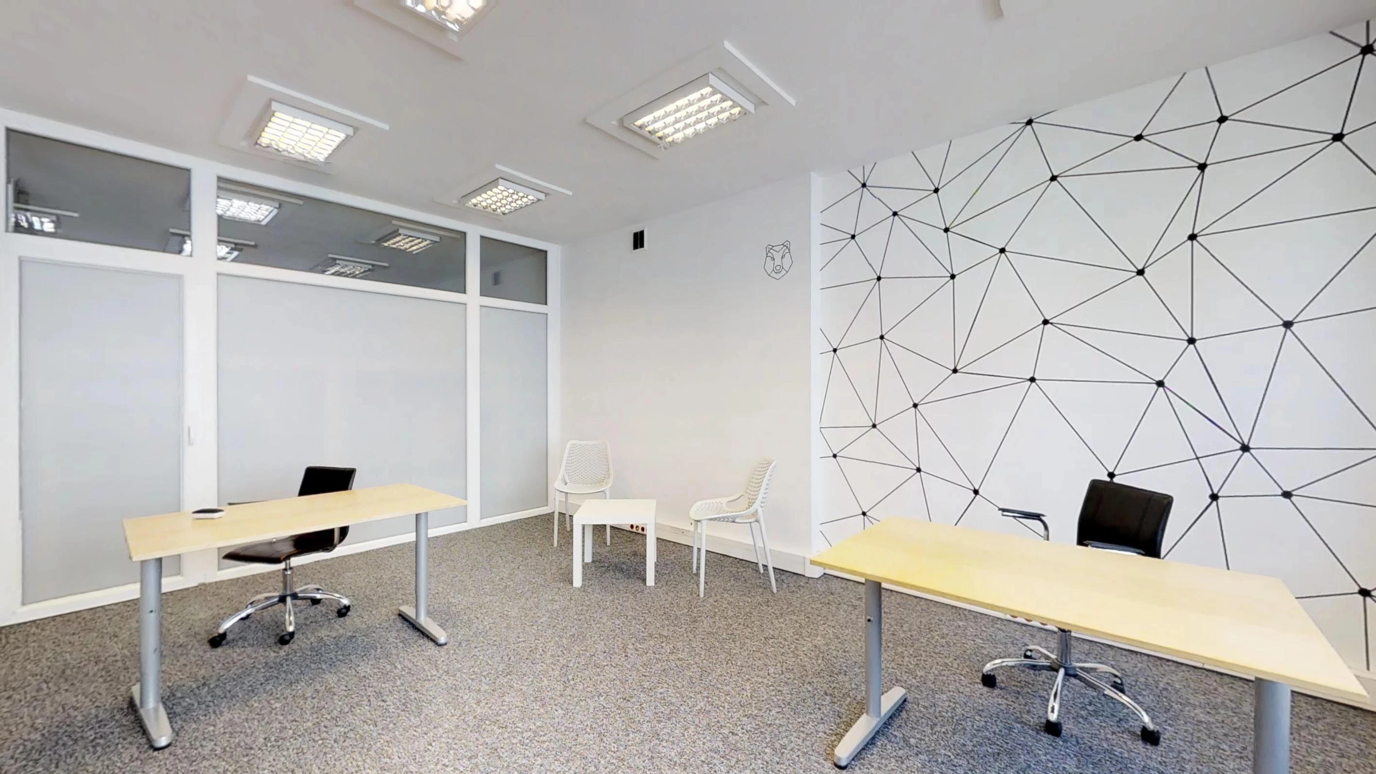Biuro z dwoma biurkami, białymi krzesłami, przeszkloną ścianką i geometrycznym muralem
